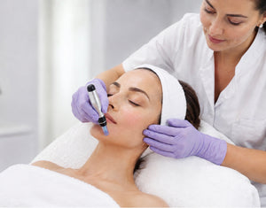 Esthetician performing a facial revitalization microneedling treatment on a client